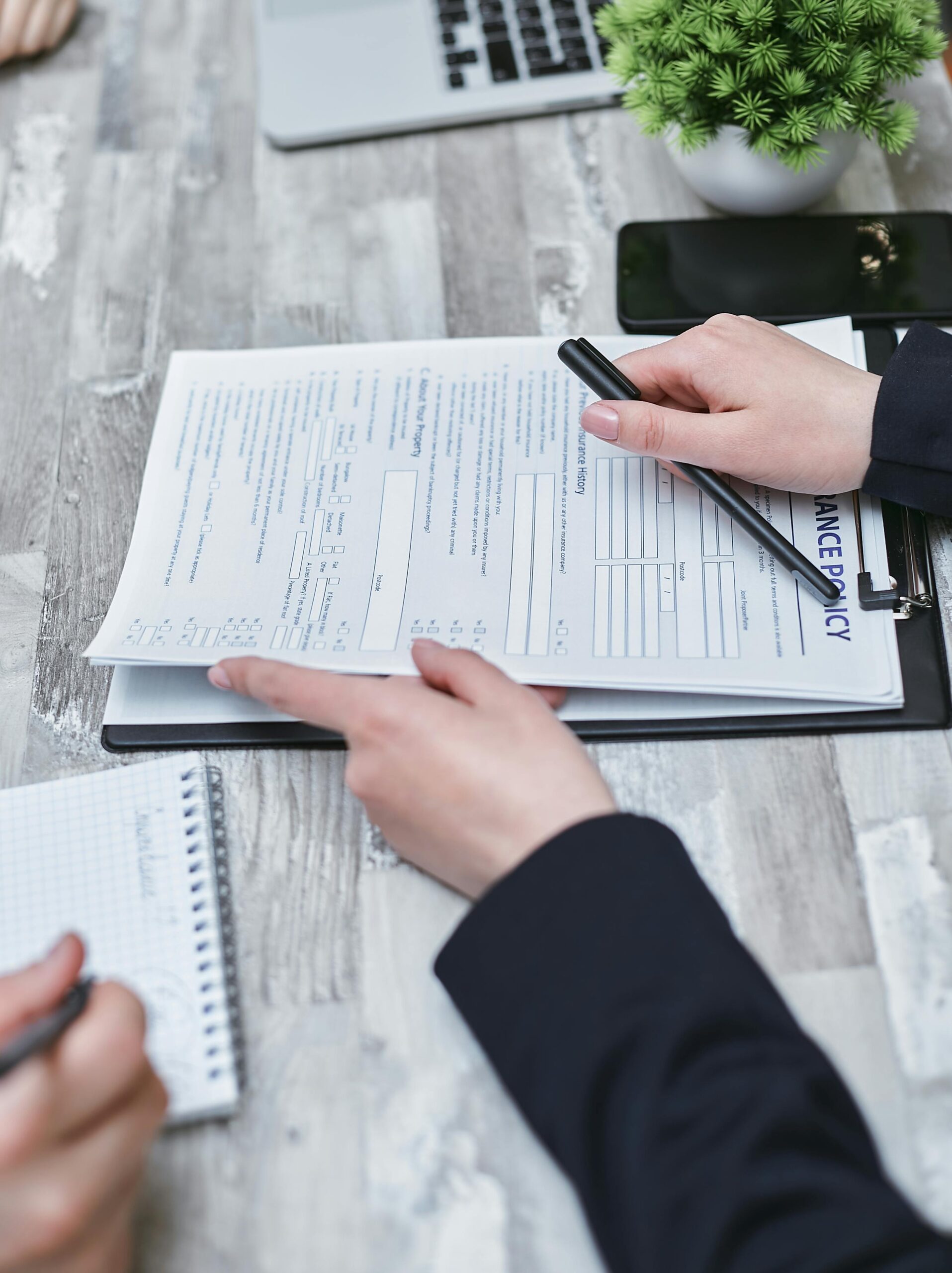 Free Close-up of hands analyzing insurance policy paperwork with pen on table. Stock Photo
